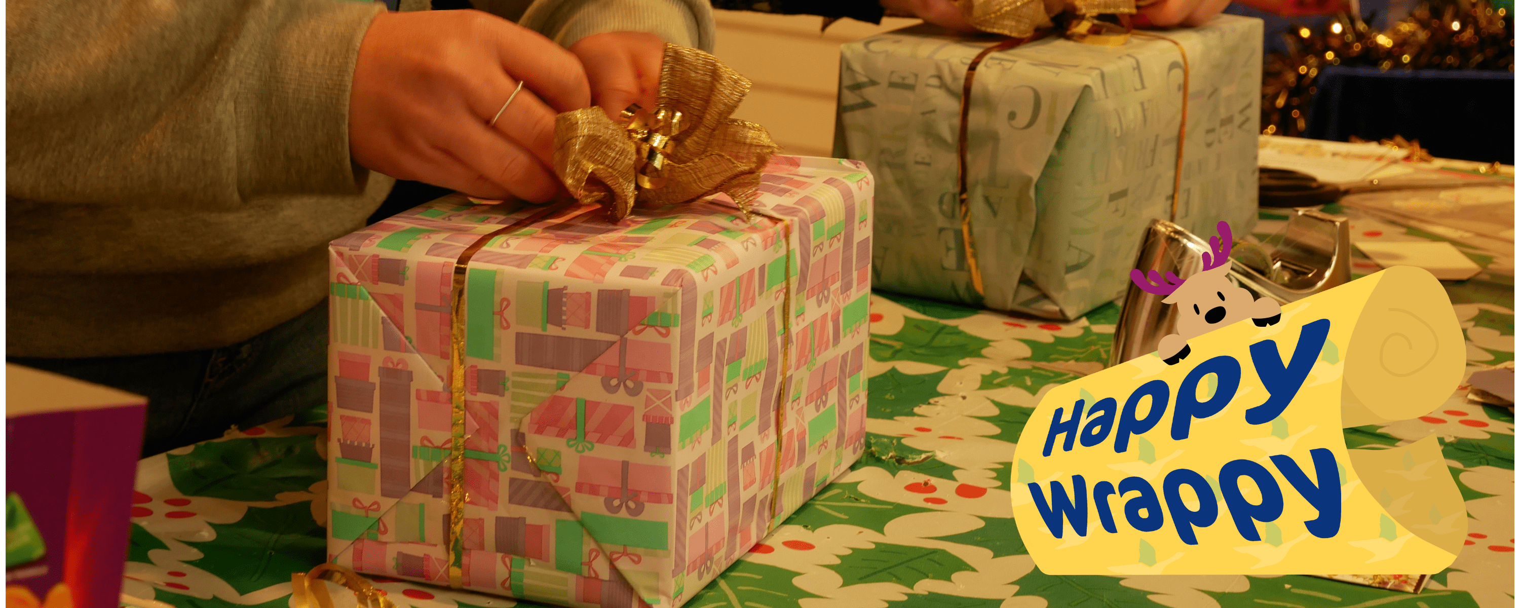 Close up of two people's hands wrapping Christmas presents with festive paper and bows