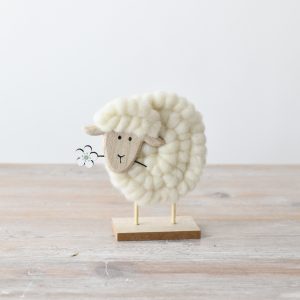 Fluffy sheep holding a flower in its mouth